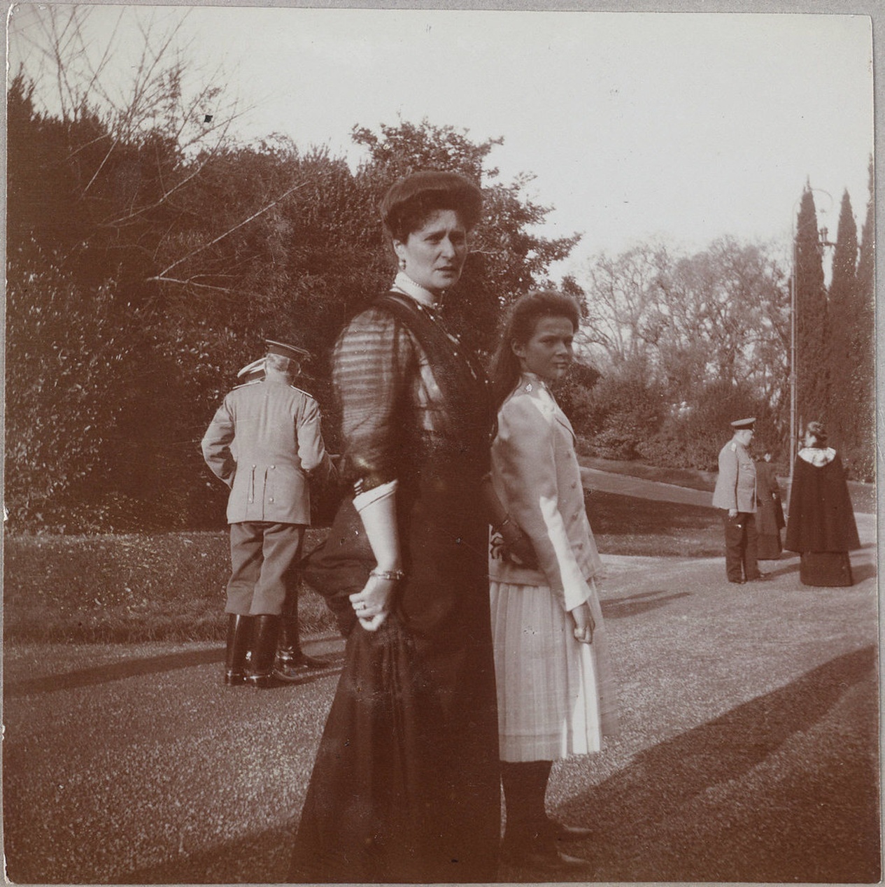 Ett sepiatonat vintagefotografi av formellt klädda personer från tidigt 1900-tal, vilket illustrerar kontrasten till dagens dynamiska barnmode.