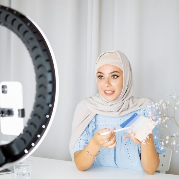 Person i hijab framför en ringlampa och mobil under videoinspelning