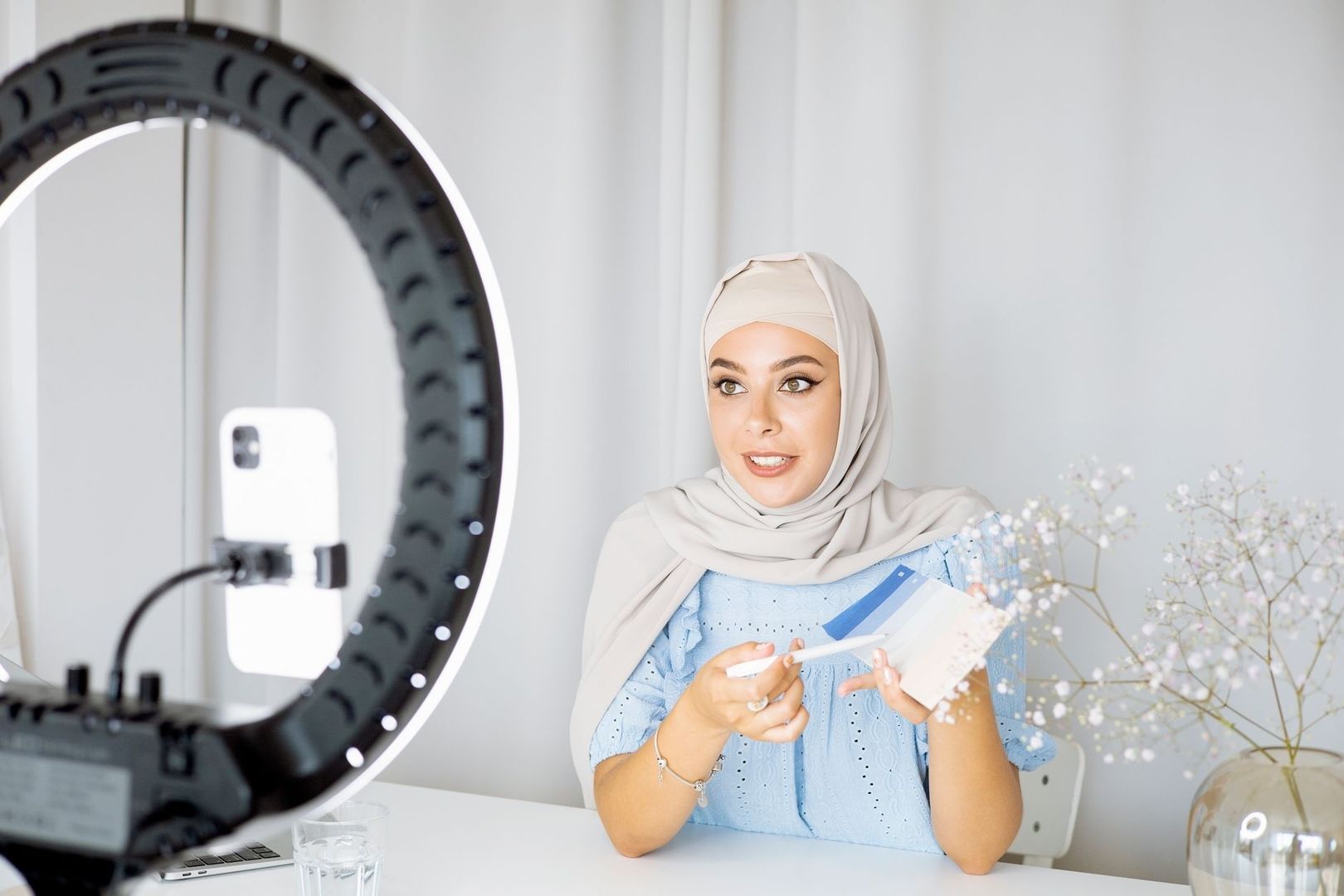 Person i hijab framför en ringlampa och mobil under videoinspelning