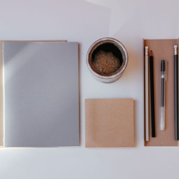 Minimalistiskt skrivbord med anteckningsböcker, kaffe och pennor